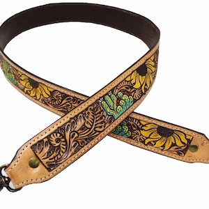 May include: A tan leather strap with a floral design featuring sunflowers and cacti. The strap has a brass swivel clasp.