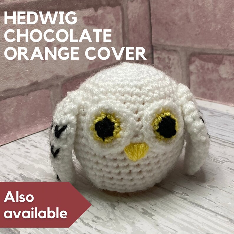 K&ouml;nnte beinhalten: Wei&szlig;e geh&auml;kelte Eule mit schwarzen und gelben Augen. Die Eule sitzt auf einer wei&szlig;en Oberfl&auml;che. Der Text "HEDWIG CHOCOLATE ORANGE COVER" befindet sich &uuml;ber der Eule. Der Text "Also available" befindet sich unter der Eule.
