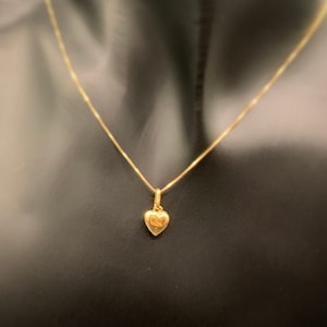 May include: A gold chain necklace with a small heart pendant.