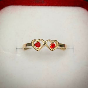 May include: A gold ring with two red heart-shaped stones.