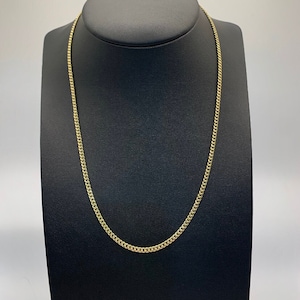 May include: A gold chain necklace with a curb link style. The chain is displayed on a black mannequin.