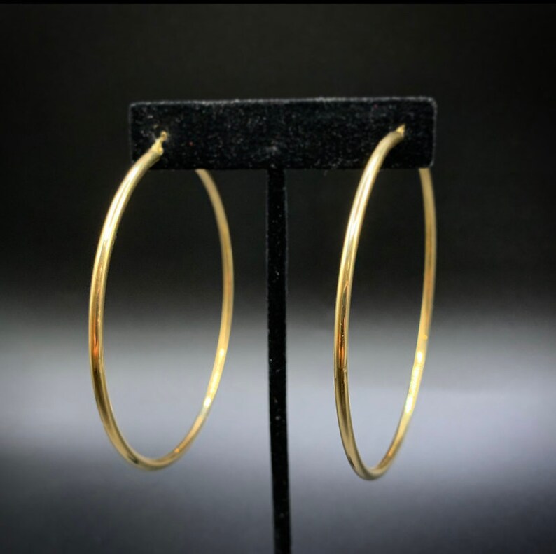 Pode incluir: Um par de brincos de argola de ouro. Os brincos s&atilde;o simples e elegantes, e seriam uma &oacute;tima adi&ccedil;&atilde;o a qualquer cole&ccedil;&atilde;o de joias.