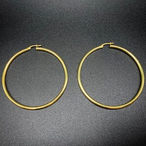 Pode incluir: Um par de brincos de argola de ouro. Os brincos s&atilde;o grandes e de forma circular.