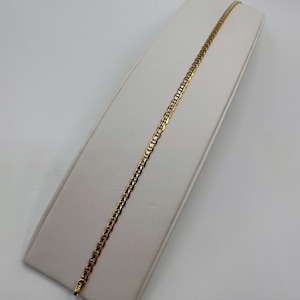 May include: A gold chain necklace with a mariner link design. The chain is displayed on a white display stand.