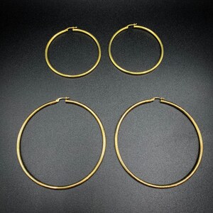 Pode incluir: Quatro brincos de argola de ouro em tamanhos diferentes. Os brincos s&atilde;o todos de metal liso e brilhante.