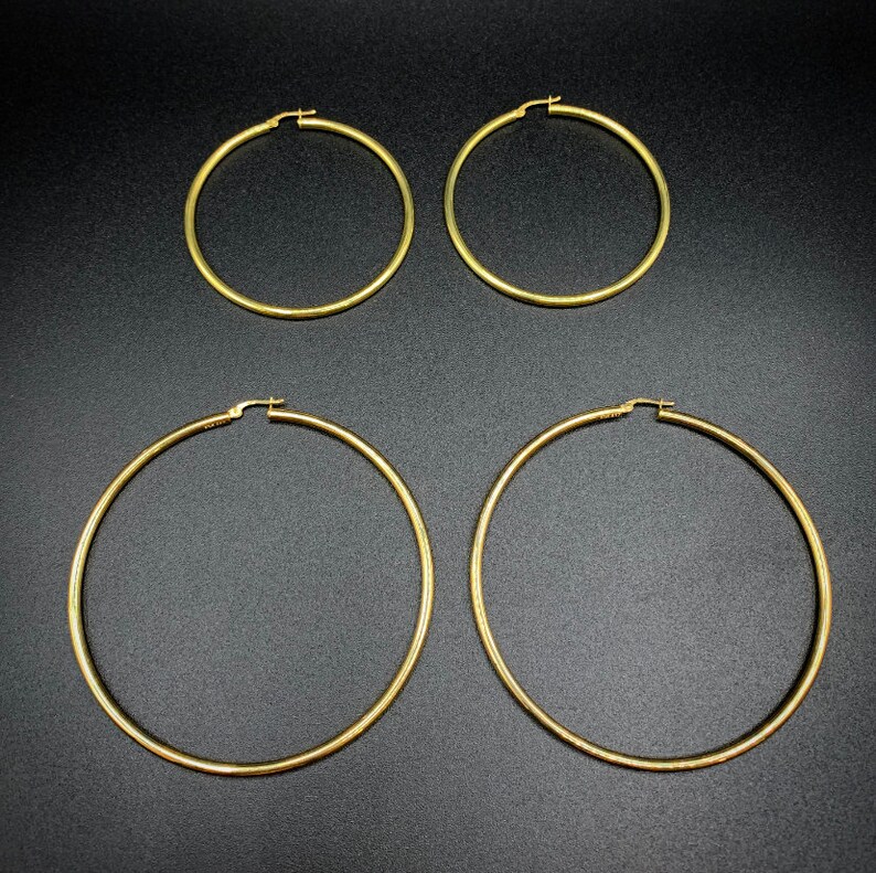 Pode incluir: Quatro brincos de argola de ouro em tamanhos diferentes. Os brincos s&atilde;o todos de metal liso e brilhante.