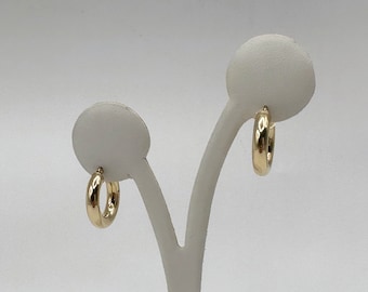 Pode incluir: Um par de brincos de argola de ouro em um expositor branco.