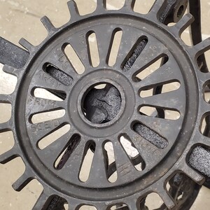 May include: Close-up of a black metal gear with the words "Seed" and "Away" visible on the surface. The gear has a circular shape with a central hole and a series of spokes radiating outwards.