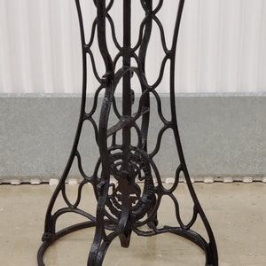 May include: Black metal table base with a circular top and intricate, decorative, openwork design. The base is made of cast iron and has a distressed finish.