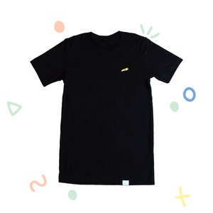 Puede incluir: Una camiseta negra con un pequeño diseño amarillo y rojo en la parte delantera.