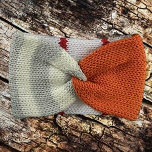 May include: A knitted headband with a twisted design. One side is a white and gray striped pattern, and the other side is a solid orange.