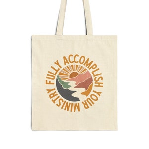 May include: A beige tote bag with a circular design featuring a sunset, mountains, and the text "FULLY ACCOMPLISH YOUR MINISTRY".