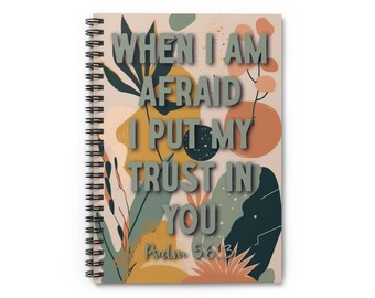 May include: A spiral bound notebook with a beige cover featuring an abstract floral design in shades of green, brown, and orange. The text "WHEN I AM AFRAID I PUT MY TRUST IN YOU" is printed in gray on the cover, along with the text "Psalm 56:3".