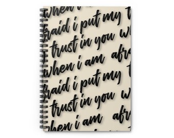 May include: A spiral bound notebook with a beige cover and black text that reads "When I am afraid I put my trust in you when I am afraid I put my trust in you when I am afraid I put my trust in you".