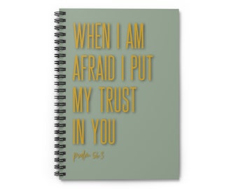 May include: A sage green spiral notebook with the text "WHEN I AM AFRAID I PUT MY TRUST IN YOU" in gold lettering. The text "Psalm 56:3" is also in gold lettering at the bottom of the notebook.
