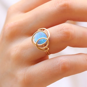 May include: A gold ring with a blue opal gemstone set in a wire design.