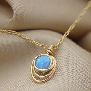 May include: A gold necklace with a blue opal pendant set in a triple circle design.