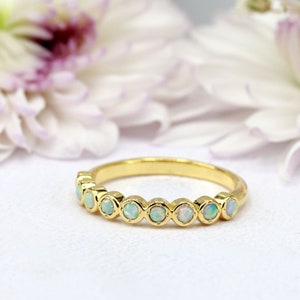 May include: A gold band ring with a row of white opal stones set in bezel settings.