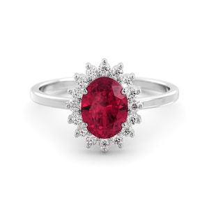 Può includere: Un anello d'argento con un grande rubino ovale circondato da un'aureola di diamanti più piccoli.
