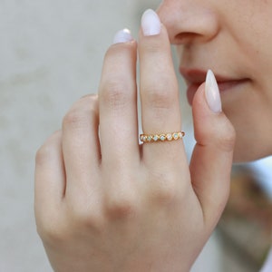 May include: A gold band ring with a row of small, white opal stones.