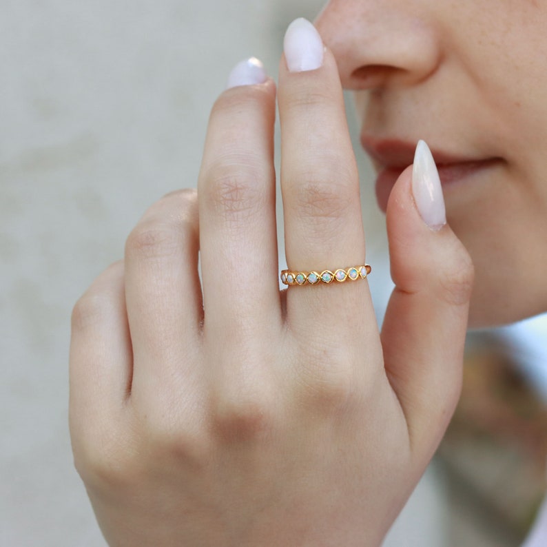 May include: A gold band ring with a row of small, white opal stones.