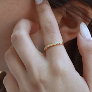 May include: A gold band ring with a row of white opal stones.