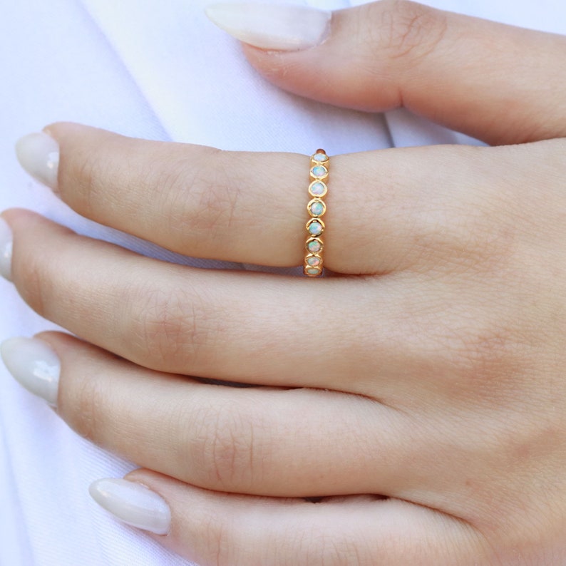 May include: A gold band ring with a row of small, white opal stones.