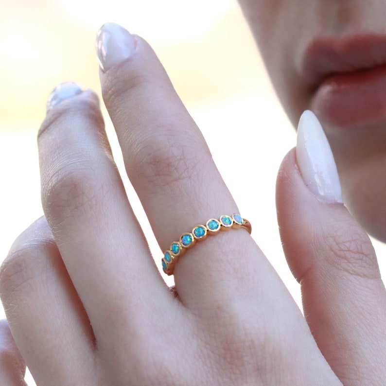 K&ouml;nnte beinhalten: Ein Goldring mit einer Reihe von hellblauen Opal-Steinen.