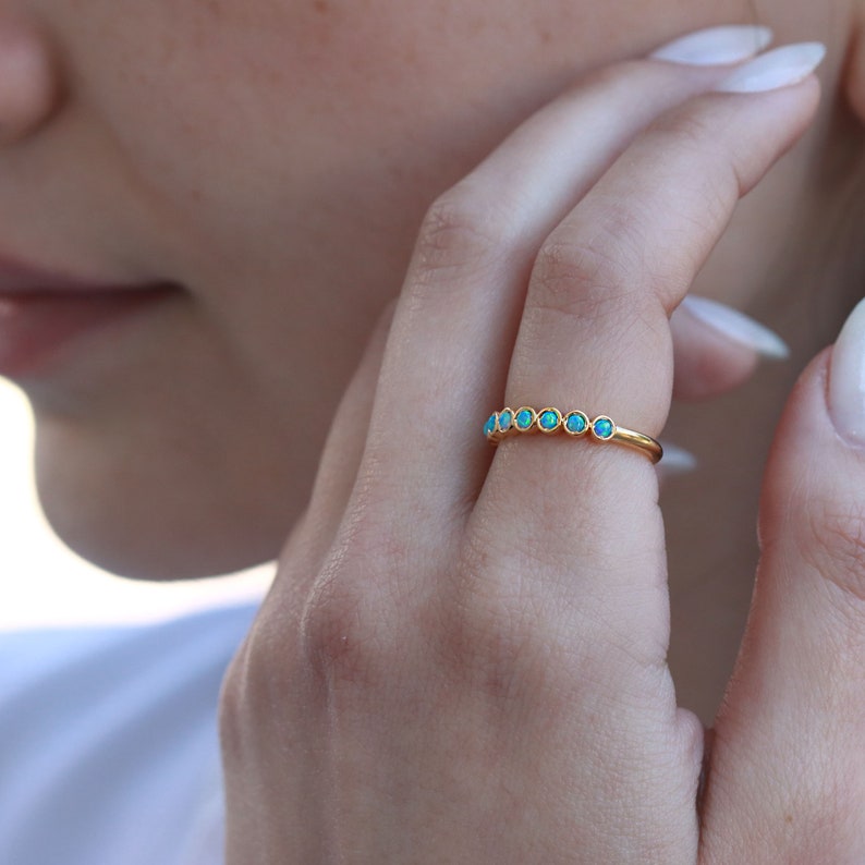 K&ouml;nnte beinhalten: Ein Goldring mit einer Reihe kleiner t&uuml;rkisblauer Opal-Steine.