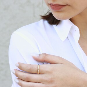 May include: A gold band ring with a row of small, clear gemstones.