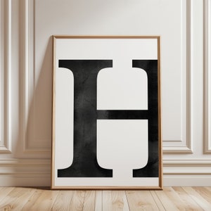Puede incluir: Una impresión enmarcada en blanco y negro de la letra H. La letra está en una fuente en negrita y en bloque y tiene un efecto texturizado, similar a la acuarela.