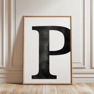 Peut inclure: Une impression aquarelle en noir et blanc de la lettre "P" dans une police simple et moderne. La lettre est centrée sur un fond blanc et encadrée dans un cadre en bois clair.
