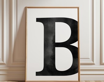 May include: A black and white watercolor print of the letter "B" in a simple, modern style. The letter is framed in a light wood frame.