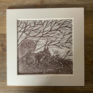 May include: A brown and white linocut print of a squirrel in a forest setting. The squirrel is in the foreground, with trees and a small house in the background. The print is titled "Autumn's Arrival."