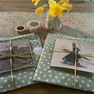 May include: Two wrapped gifts with green and white polka dot paper. One gift is tied with a gold ribbon and features a black and white print of a bird. The other gift is tied with a gold ribbon and features a black and white print of a rabbit.