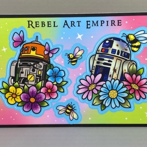 May include: A colorful illustration of two Star Wars droids, R2-D2 and a droid with orange accents, surrounded by flowers and bees. The text "REBEL ART EMPIRE" is at the top of the image.