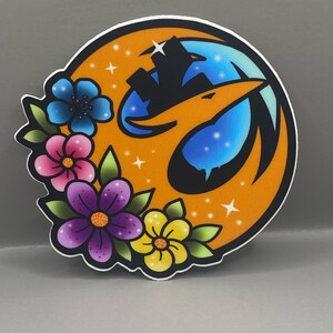 May include: A round sticker featuring an orange emblem with a black silhouette of a structure and a stylized bird. The emblem is surrounded by colorful flowers in blue, pink, purple, and yellow, with green leaves. White stars are scattered around the emblem.