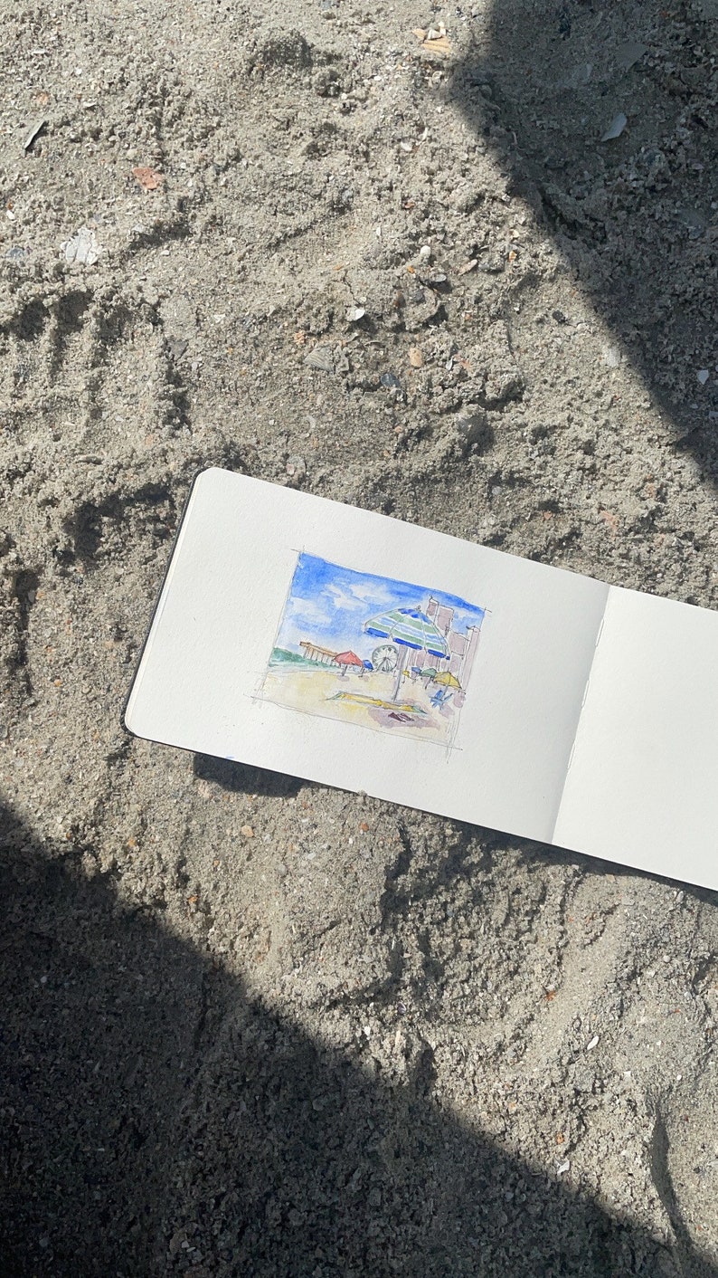 May include: A watercolor painting of a beach scene with an umbrella, a Ferris wheel, and buildings in the background.
