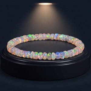 Könnte beinhalten: Ein kreisförmiges Armband aus kleinen, durchscheinenden äthiopischen Welo-Opalperlen mit irisierenden Farbspielen. Der Text lautet: Natural Gemstone — Certified Authentic, Handcrafted Artisan Jewelry, 100% Ethiopian Welo Opal, Natural Stone — Unique Color Play.