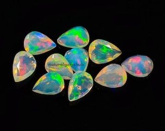 May include: A collection of ten pear-shaped opals, each displaying a play of color with iridescent flashes of green, blue, and red. The opals are set against a black background, highlighting their vibrant hues and unique patterns.