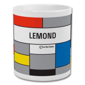 May include: White ceramic mug with a colourful geometric design featuring red, yellow, blue, and grey blocks. The word "LEMOND" is printed in black, with "La Vie Claire" logo below. A modern and artistic design.