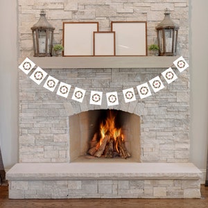 May include: A white Christmas advent calendar banner with red numbers hanging above a fireplace with a roaring fire. The banner has a wreath design with green leaves and brown berries.