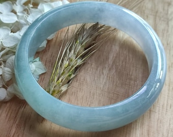 May include: A light blue jade bangle bracelet. The bangle is smooth and polished, with a subtle sheen.