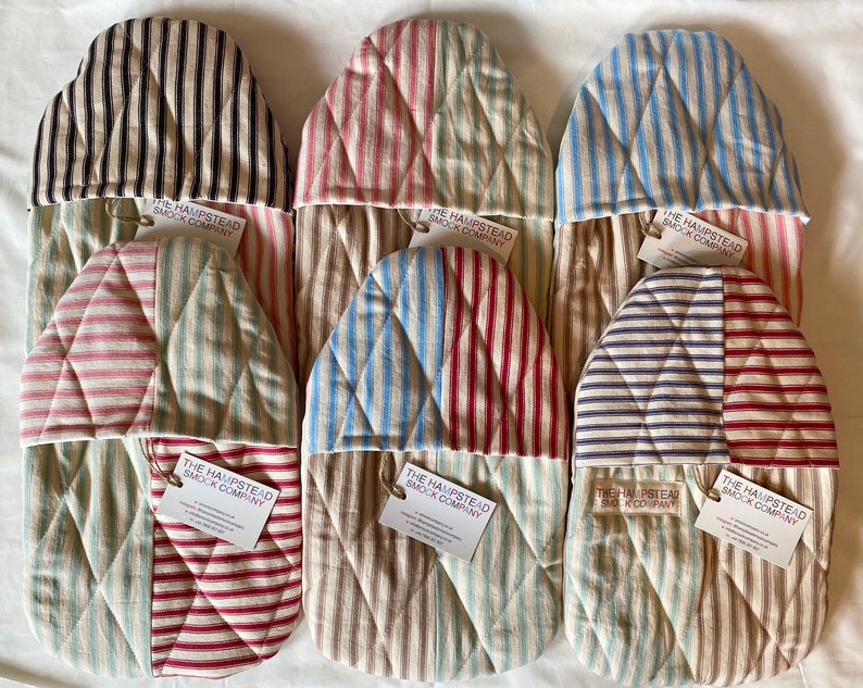 Pode incluir: Seis luvas de forno acolchoadas com tecido listrado em v&aacute;rias cores, incluindo vermelho, azul, verde e preto. Cada luva tem uma etiqueta que diz "The Hampstead Smock Company".
