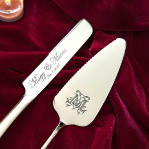 Peut inclure: Un ensemble de couteau et de serveur à gâteau en argent avec l'inscription "Maggy & Minas June 17, 2023" et un monogramme "M" sur le serveur.