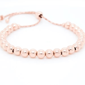 Pode incluir: Um bracelete de contas de ouro rosa com fecho deslizante ajustável.