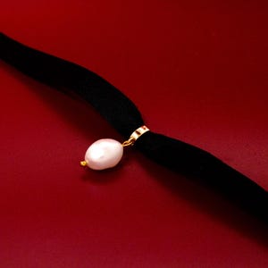 May include: A black velvet choker necklace with a single white pearl pendant.