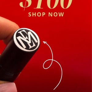 May include: A red background with the text "GIFTS UNDER $100 SHOP NOW". A black and white monogram stamp is shown with an arrow pointing to the text "your monogram here".