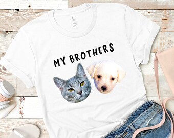 Puede incluir: Camiseta blanca con el texto "MY BROTHERS" impreso en ella. Un gato gris y un cachorro blanco aparecen en la camiseta.