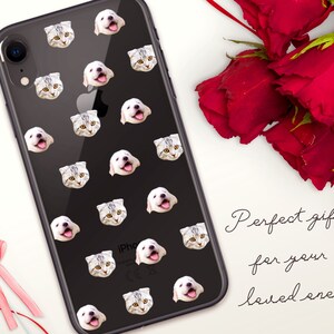 May include: A black iPhone case with a repeating pattern of white cat and dog faces. The case is on a white surface with a red rose and a red heart.
